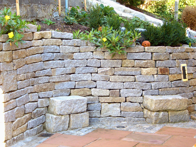 Granitsteinmauer mit bepflanztem Beet