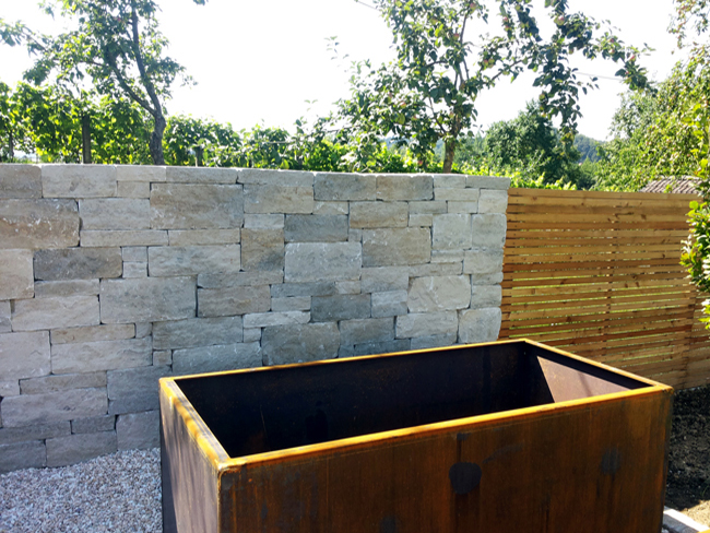 Kalksteinmauer als Abgrenzung des Gartens und Sichtschutz